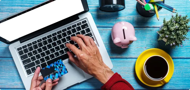 Un paiement en ligne sur un ordinateur portable, à côté d'une tirelire et d'une tasse de café